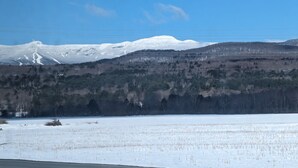 A snowy landscape with a mountain in the background, a forested area, and a clear sky. - Stowe Retreat Mountain Views & Fenced Backyard by RedAwning (Stowe)