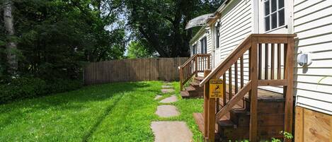 A wooden deck leading to a house with a caution sign warning of slippery steps when wet or icy.