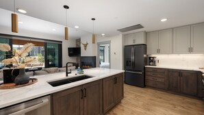 A modern kitchen with a large island, stainless steel appliances, and a fireplace. - Timber Fox 1208 3 Bedroom Apts by RedAwning (Winter Park)