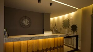 A reception area with a marble counter, a wall clock, and a mural of architectural elements.