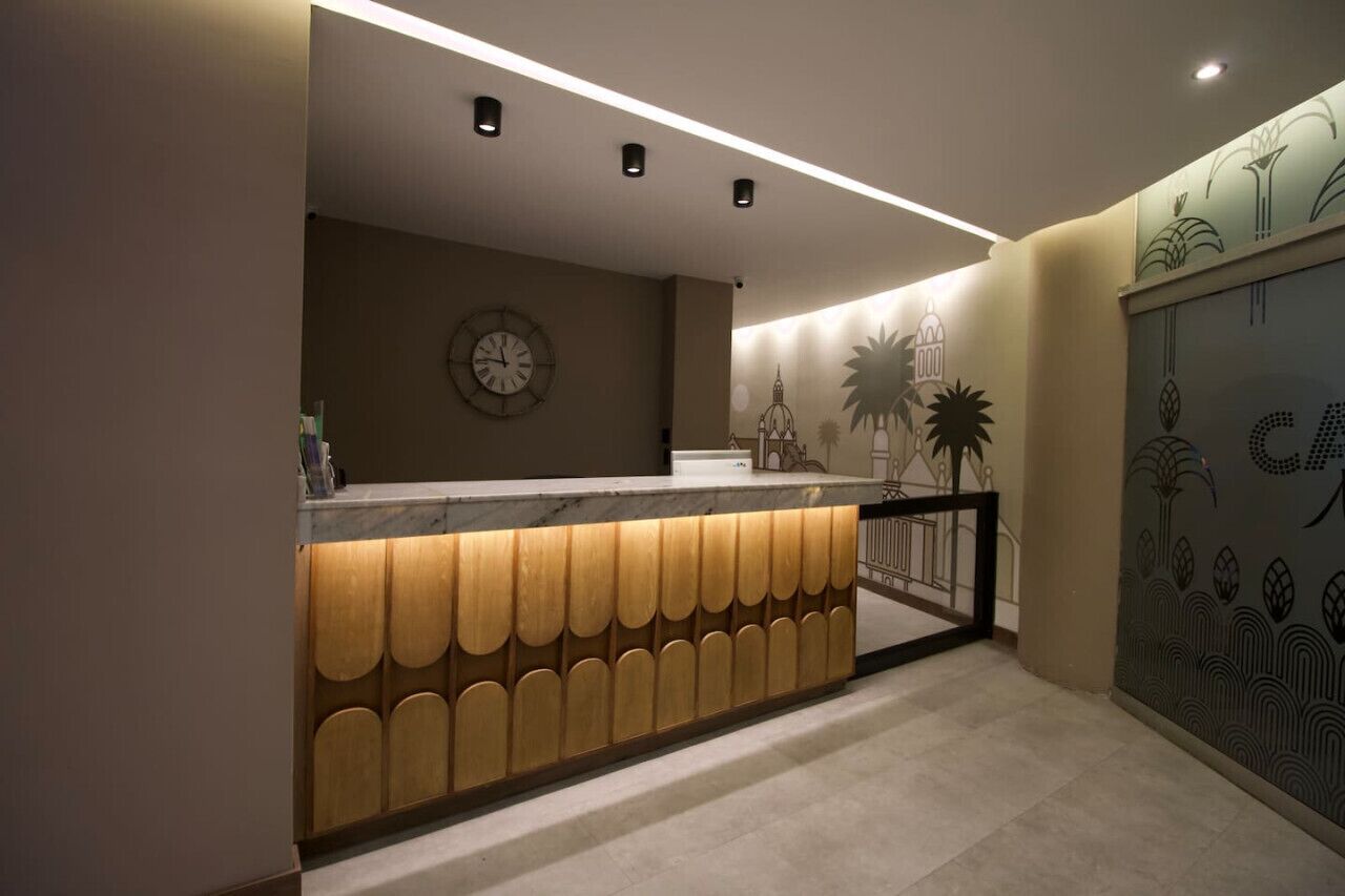Una zona de recepción con un mostrador de madera, un reloj y una pared con diseños decorativos.