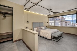 Relax in this serene bedroom with a large bed, city and mountain views, and a cozy bench at the foot.
