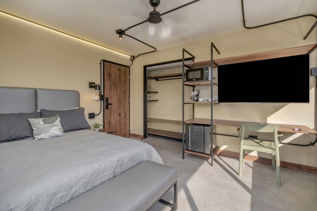 Un dormitorio moderno con cama, escritorio y televisión.