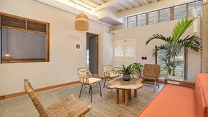 Une pièce meublée de meubles en osier, avec une table ronde en bois et une table de billard.