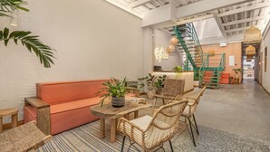 Un intérieur chaleureux avec une table en bois, des chaises en osier, un canapé moelleux et un escalier doté d’une rampe verte.