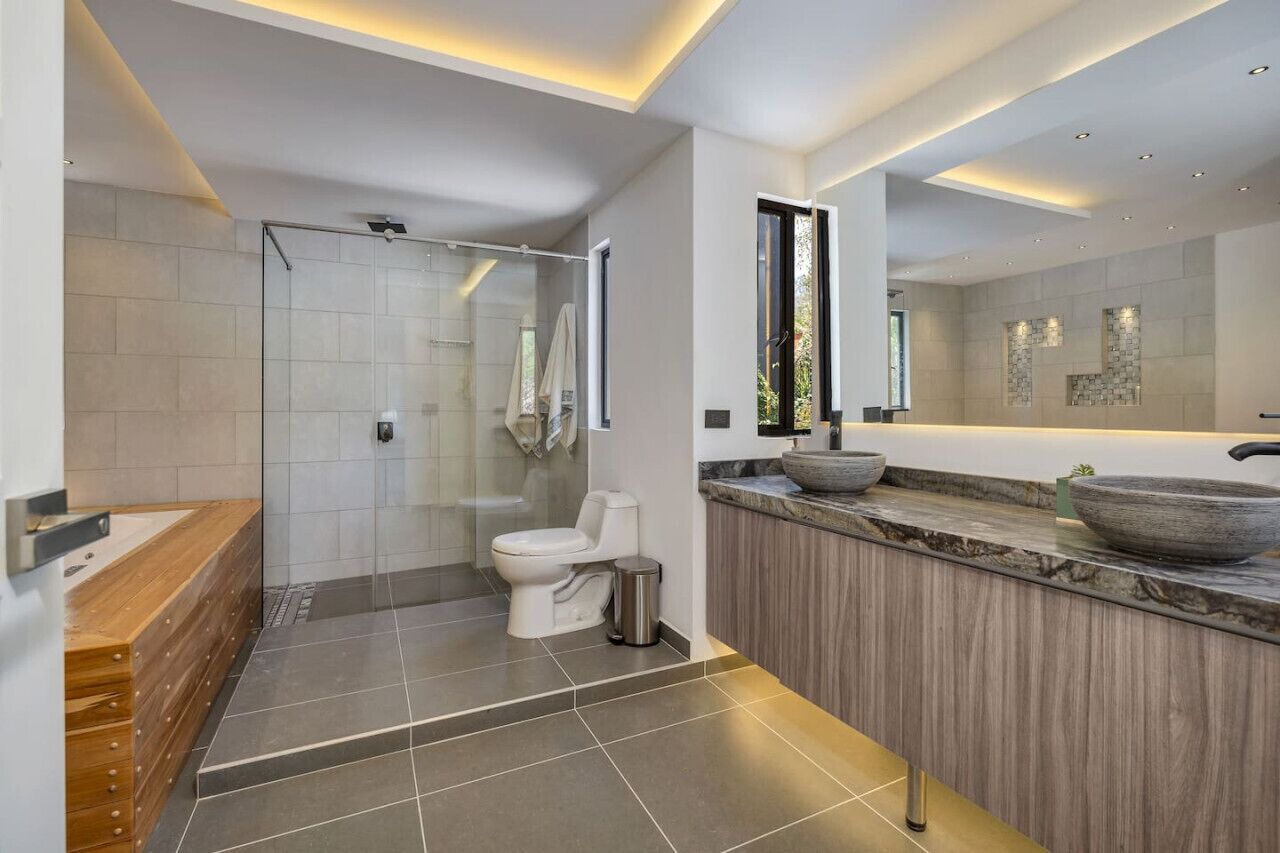 A modern bathroom with a glass-enclosed shower, a wooden vanity, and a large mirror.