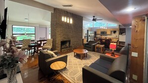 A spacious living room with a fireplace, modern furniture, and a view of the outdoors. - 5-Bedroom 6000SF wood and glass retreat in Atlanta, surrounded by greenery.   (Atlanta)