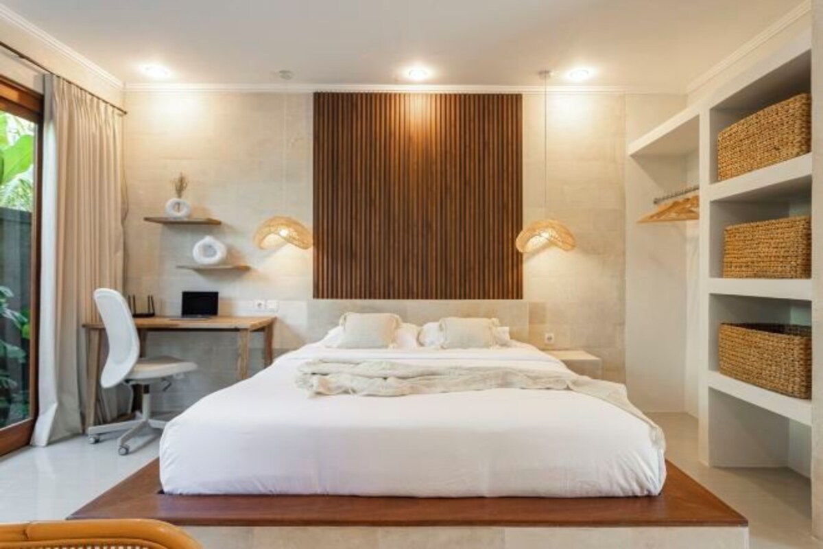 Una habitación de hotel moderna con una cama grande, un escritorio y una computadora.