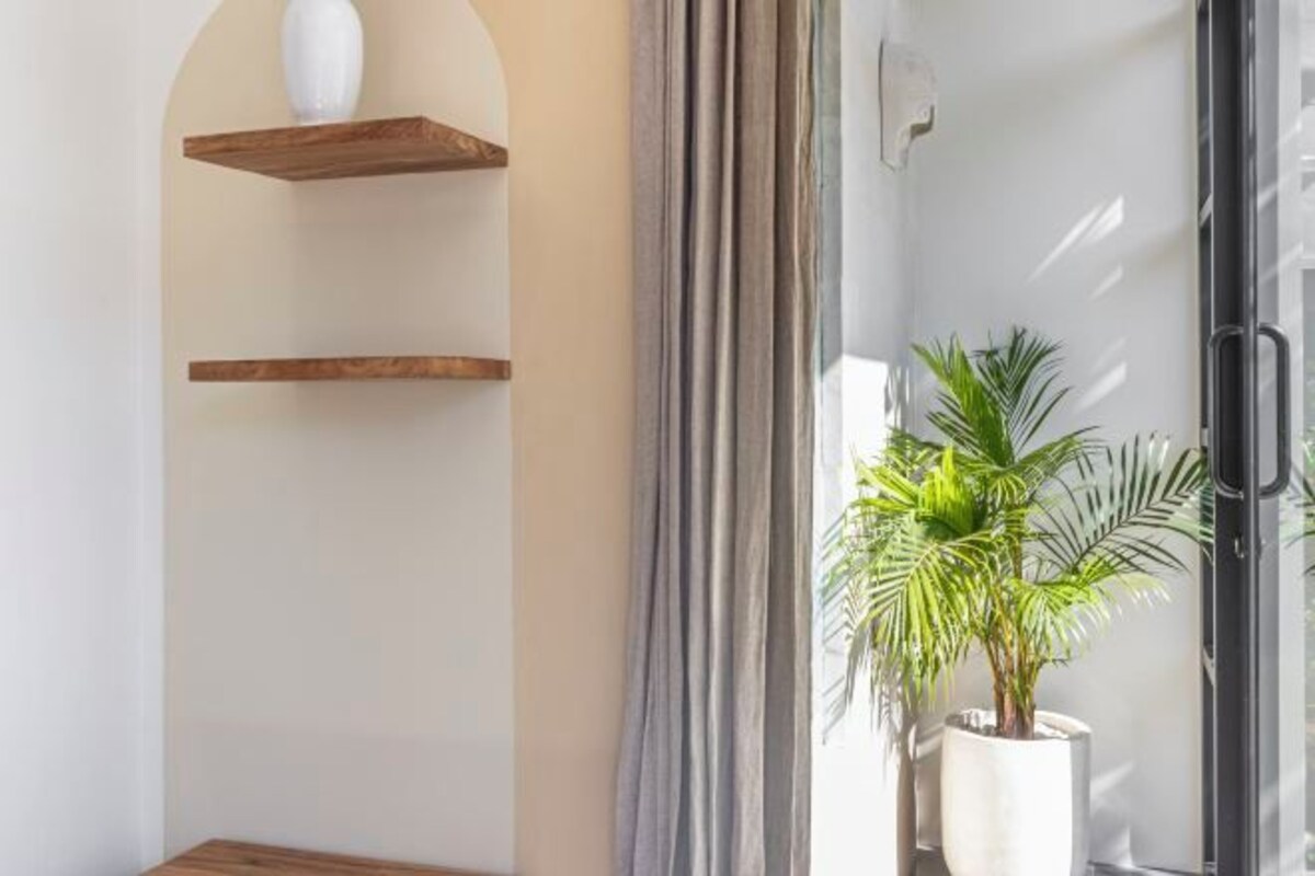Un baño moderno con estantes de madera, una planta en maceta y una cabina de ducha de vidrio.