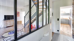 Un interior moderno con pared de vidrio, una escalera, un comedor y una cocina.