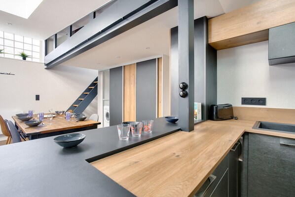 A modern kitchen with a wooden countertop, a built-in dishwasher, and a toaster.