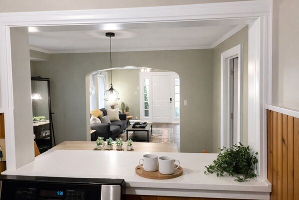 Una cocina moderna con una isla central, una zona de comedor con sofá y mesa de centro, y vistas al salón.