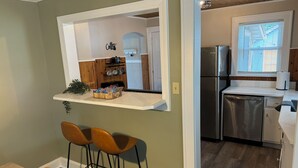 A kitchen with a built-in refrigerator, a sink, and a window with blinds. There is a bar area with stools and a shelf with snacks. - Hot Tub+Arcade / Fire Pit Retreat Near Monon Trail (Indianapolis)
