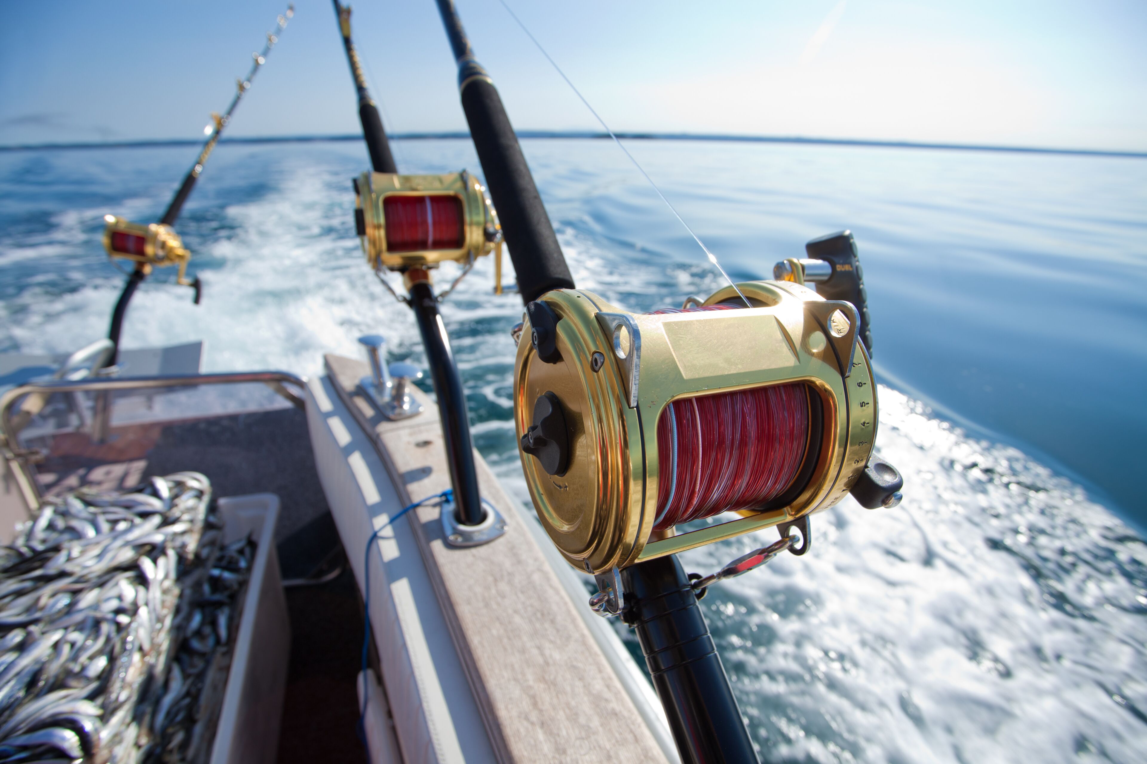 A fishing rod reel on a boat with a view of the ocean.