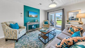 A living room with a teal accent wall, a fireplace, a sofa, and a coffee table. - 🏖️Tradewinds 21 - Coastal Charm | Easy Beach Access | Steps to Pool🏖️ (Miramar Beach)