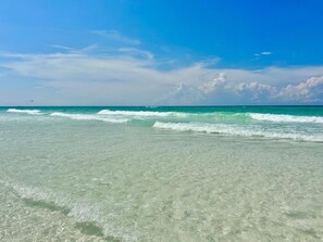 A beach with clear turquoise water and a clear sky.