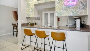 A kitchen with a bar area, a neon sign, and a sign indicating optional swimwear. - The Springs: Luxury Resort Living, Palm Springs (Palm Springs)