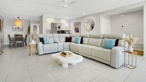 A modern living room with a sectional sofa, a dining table, and a kitchen in the background. - The Springs: Luxury Resort Living, Palm Springs (Palm Springs)