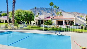A swimming pool with a white fence, palm trees, and a mountain in the background. - The Springs: Luxury Resort Living, Palm Springs (Palm Springs)