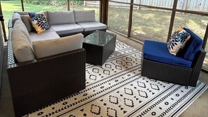 Un espace extérieur aménagé en terrasse, avec un ensemble de canapés, une table basse et un tapis à motifs.