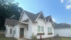 Une maison de plain-pied avec un toit à pignon, un porche à l’avant et le numéro « 573 » affiché sur le côté.