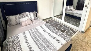 Una camera da letto con un letto, una ventola a soffitto, uno specchio grande e un quadro appeso al muro.