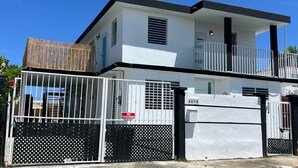 Un edificio di due piani con un balcone, un ingresso carrabile e un cartello che indica divieto di parcheggio.