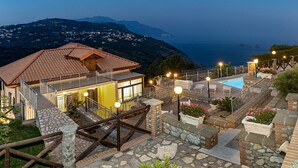 Une villa avec piscine, des allées pavées de pierres et une vue sur la mer.