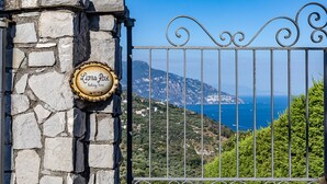 Un mur de pierre sur lequel est apposée une plaque indiquant « Lions Rose, maison de vacances », et une porte en métal donnant sur un paysage côtier.