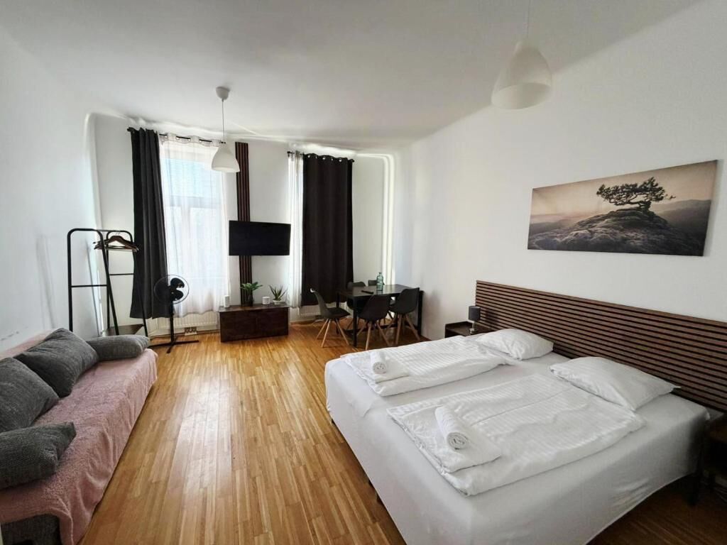 A hotel room with a bed, a desk, a chair, a TV, and a painting on the wall.