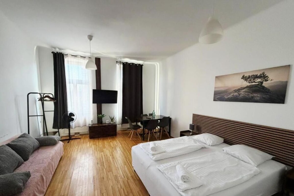 A hotel room with a bed, a desk, a chair, a TV, and a painting on the wall.