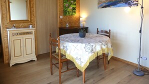 Un coin repas comprenant une table, des chaises, un buffet, un miroir, une horloge, une lampe fixée au mur et un tableau.