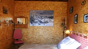 Habitació amb panells de fusta, un llit, una cadira, un quadre amb marc i una làmpada.