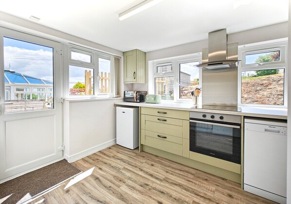 Kitchen features an oven, microwave, and dishwasher, with a window offering a view of the outside.