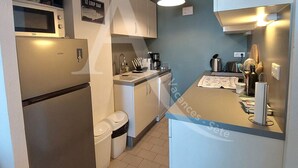 Une cuisine compacte équipée d’un four à micro-ondes, d’un réfrigérateur, d’un évier et d’un luminaire suspendu.