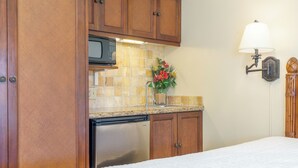 A kitchen with wooden cabinets, a stainless steel refrigerator, a microwave, and a sink with a vase of flowers. - Studio w/Ocean Views - Islander On The Beach 322 (Kapa'a)