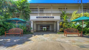 A hotel entrance with a sign reading "Islander on the Beach," two wooden benches, and tropical plants. - Studio w/Ocean Views - Islander On The Beach 322 (Kapa'a)