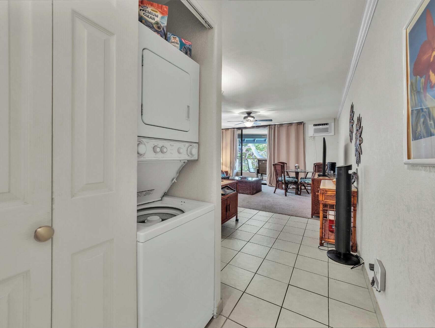 A laundry room with a washer and dryer, a dining area with a table and chairs, and a view of the outdoors through a sliding glass door.