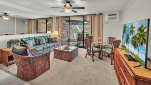 A living room with a sofa, chairs, a coffee table, and a TV.