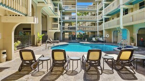 A multi-level hotel with a central swimming pool, outdoor seating, and balconies.