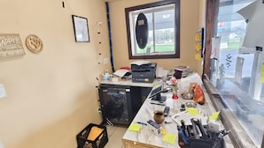 A cluttered office space with a desk, computer, printer, and various office supplies.