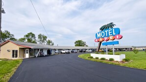 A motel with a large sign, a parking lot, and a building with a sloped roof.