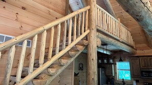 Eine Holztreppe mit Geländer, die zu einer erhöhten Empore führt.