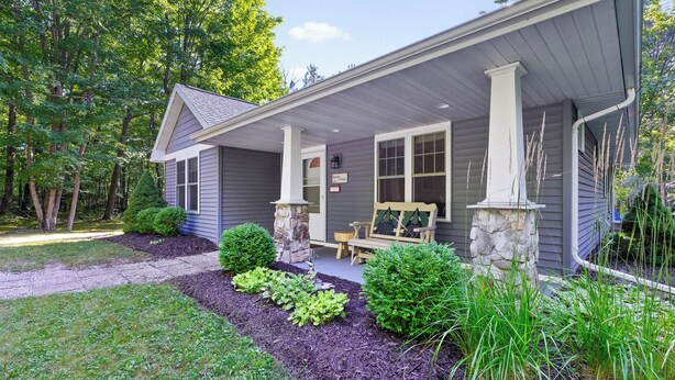 A house with a covered porch, stone pillars, and a bench. - Blue Bear Cottage: Serene Fish Creek Escape (Fish Creek)
