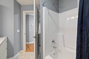 Une salle de bain équipée d’une baignoire, d’une douche et d’une porte donnant sur une autre pièce.