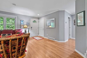 Un salon avec un canapé, une chaise en bois, une table à manger et un tapis rouge.
