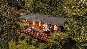 A cabin with a deck, hot tub, and outdoor seating area surrounded by trees. - Hot Tub, Fire Pit & Mountain Views + Biltmore Pass | Cozy One-Level Cabin (Waynesville)