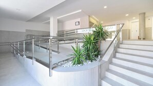 Un intérieur moderne avec un escalier à volutes, des rampes en verre et des plantes en pot.