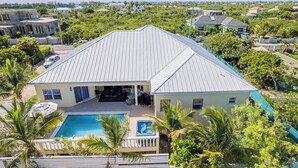 Une grande maison avec une piscine, un patio couvert et un garage.