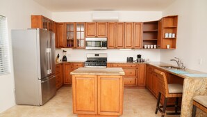 Une cuisine avec des meubles de rangement en bois, un réfrigérateur en acier inoxydable, un four à micro-ondes, une cuisinière et un évier.